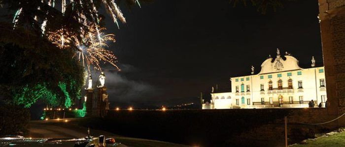 Vista notturna della Villa di Montruglio, con accenno di limousine, illuminata con il parco ed i fuochi artificiali vicino al cancello.