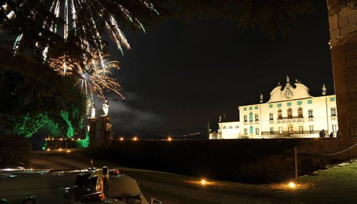 Vista notturna della Villa di Montruglio, con accenno di limousine, illuminata con il parco ed i fuochi artificiali vicino al cancello.