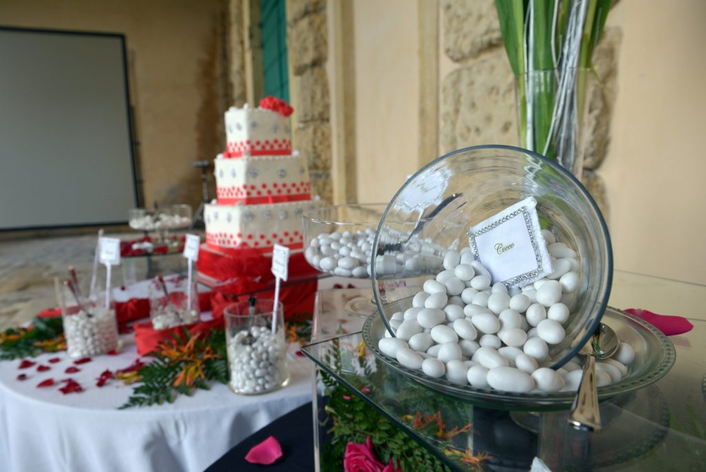 Mise en place dei confetti nuziali con decorazioni, in primo piano una boule con cucchiaio, sullo sfondo una torta.