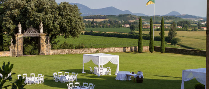 Allestimento nuziale con baldacchini, tavoli e sedie bianche nel prato di fronte la Barchessa della Villa di Montruglio.