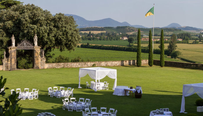 Allestimento nuziale con baldacchini, tavoli e sedie bianche nel prato di fronte la Barchessa della Villa di Montruglio.