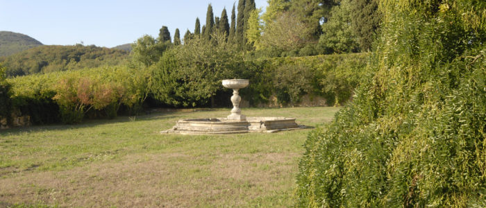 La fontana del Brolo della Villa di Montruglio, sullo sfondo una parete di cespugli.