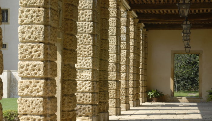 Vista del portico interno in prospettiva della Barchessa della Villa di Montruglio, delle sue colonne a pietra bugnata e delle lampade antiche.