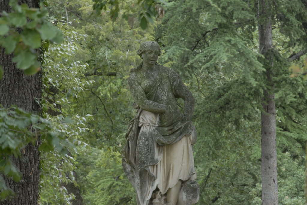 Scultura in pietra di una donna nel Parco della Villa di Montruglio. Sullo sfondo degli alberi.