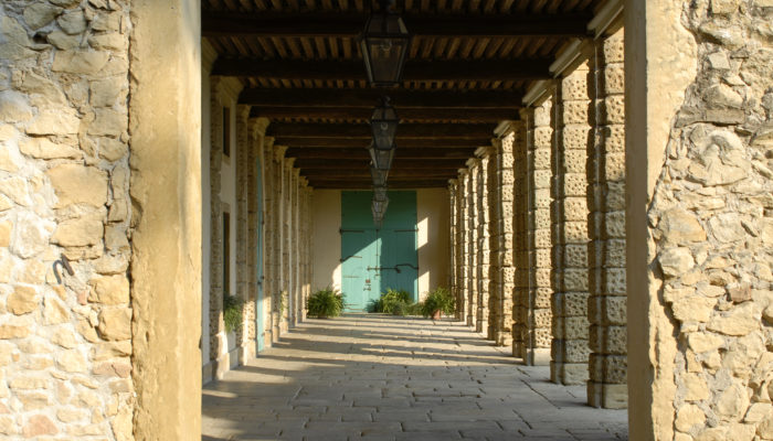 Il porticato interno della Barchessa della Villa di Montruglio in una visione speculare delle colonne sulla destra e delle porte di accesso sulla sinistra.