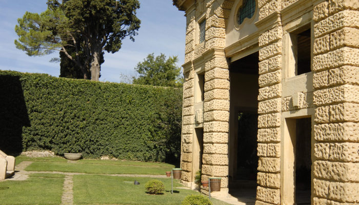 Vista laterale delle colonne in pietre bugnate della Barchessa della Villa di Montruglio, contornata dal giardino.